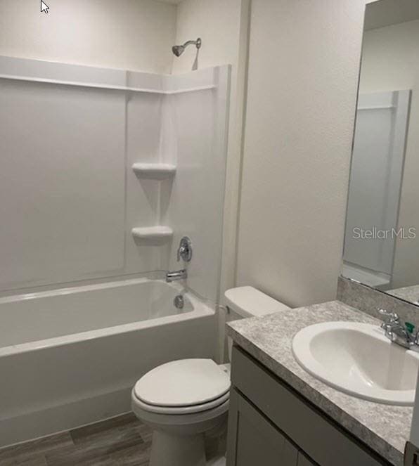 full bathroom featuring shower / washtub combination, hardwood / wood-style floors, vanity, and toilet