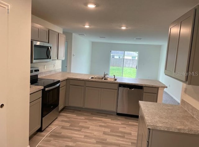 kitchen featuring light hardwood / wood-style floors, sink, kitchen peninsula, gray cabinetry, and stainless steel appliances