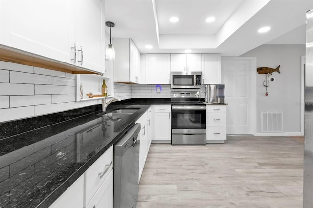 kitchen featuring appliances with stainless steel finishes, sink, hanging light fixtures, and light wood-type flooring