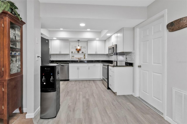 kitchen with decorative backsplash, stainless steel appliances, sink, light wood-type flooring, and white cabinetry