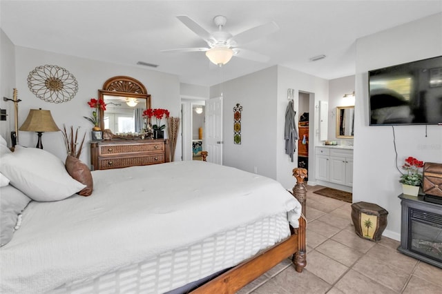 bedroom featuring connected bathroom, light tile patterned floors, and ceiling fan