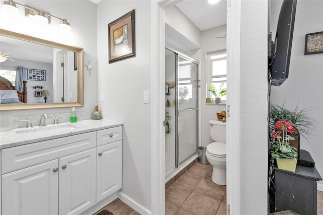 bathroom with ceiling fan, walk in shower, toilet, vanity, and tile patterned floors