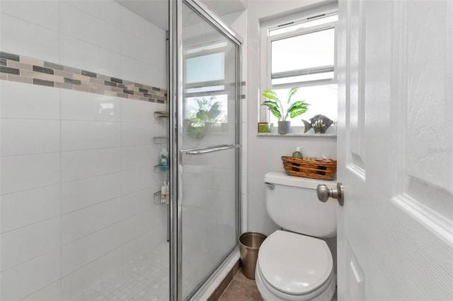 bathroom with a shower with door and toilet