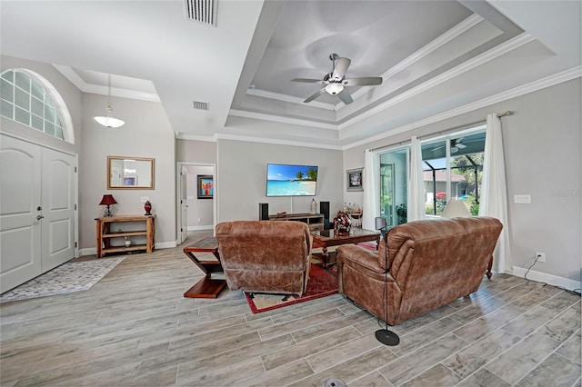 living room with ceiling fan, a raised ceiling, and ornamental molding