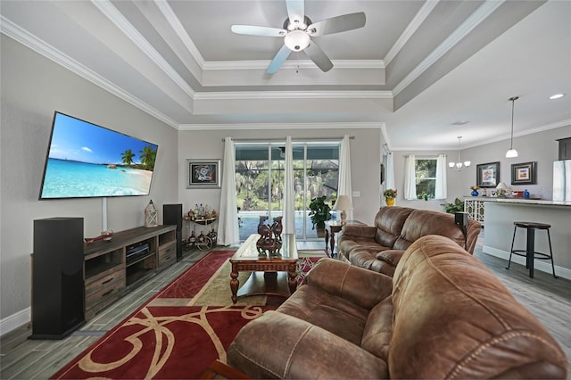 living room with hardwood / wood-style floors, ceiling fan with notable chandelier, a raised ceiling, and crown molding