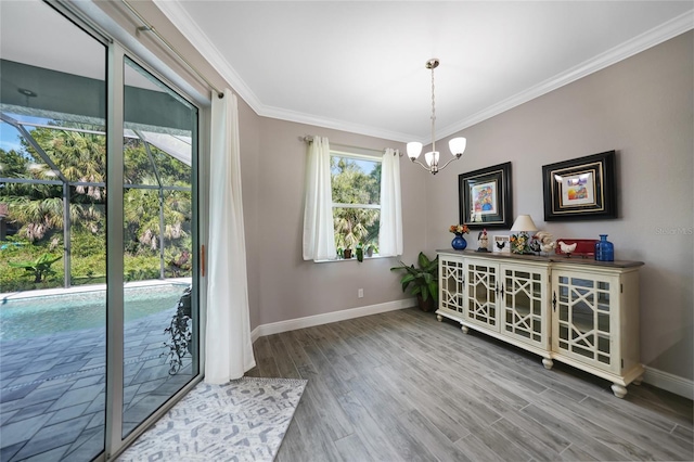 unfurnished dining area featuring a chandelier, wood-type flooring, plenty of natural light, and crown molding