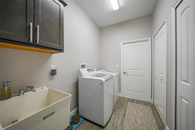 washroom with cabinets, washing machine and clothes dryer, and sink