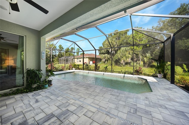 view of pool with glass enclosure, ceiling fan, and a patio area