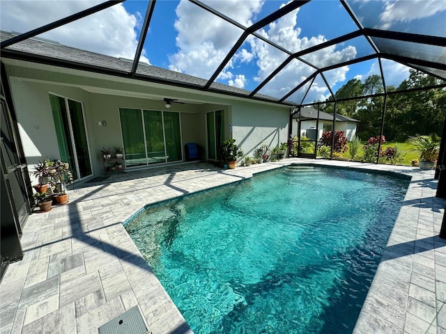 view of swimming pool featuring glass enclosure, ceiling fan, and a patio area