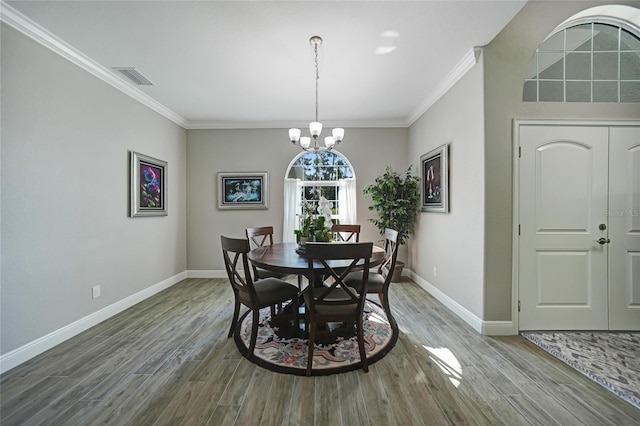 dining space with a notable chandelier, wood-type flooring, and ornamental molding