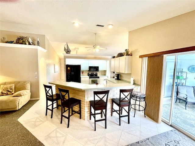 kitchen with kitchen peninsula, a breakfast bar, ceiling fan, black appliances, and white cabinetry