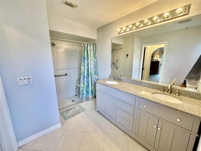 bathroom featuring a shower with shower curtain, vanity, a textured ceiling, and tile patterned floors