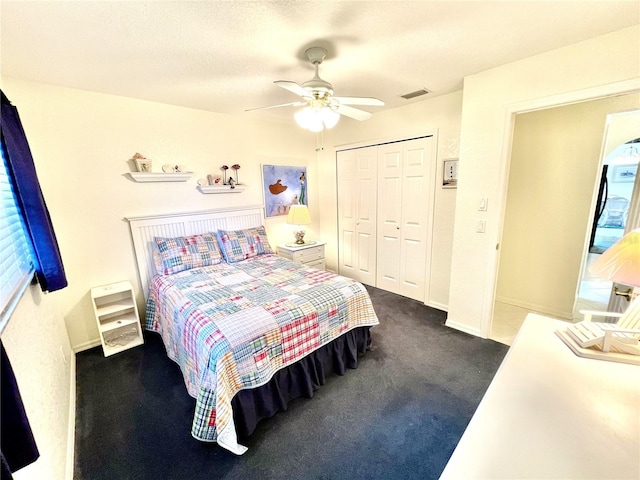 bedroom featuring ceiling fan, a closet, dark carpet, and a textured ceiling