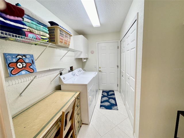 laundry area featuring cabinets, light tile patterned floors, a textured ceiling, and independent washer and dryer