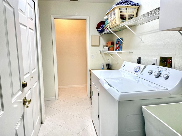 clothes washing area featuring separate washer and dryer, sink, and light tile patterned flooring