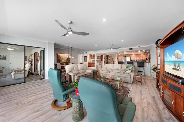 living room with light hardwood / wood-style flooring, ceiling fan, and ornamental molding