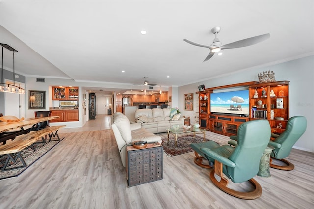 living room with ornamental molding, light hardwood / wood-style floors, and ceiling fan