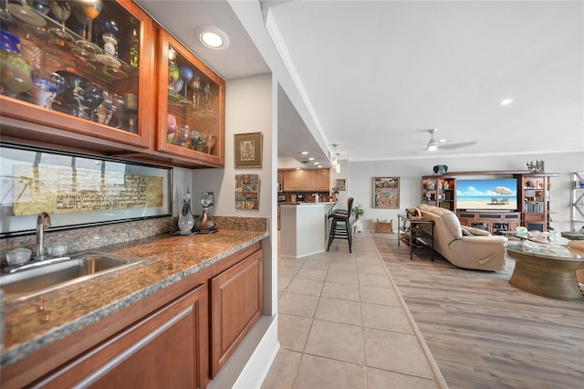 bar with ceiling fan, light tile patterned flooring, sink, stone countertops, and crown molding