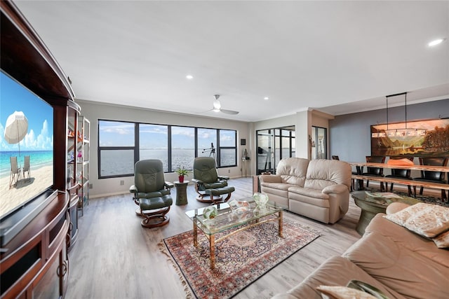 living room with ornamental molding, light wood-type flooring, a water view, and ceiling fan