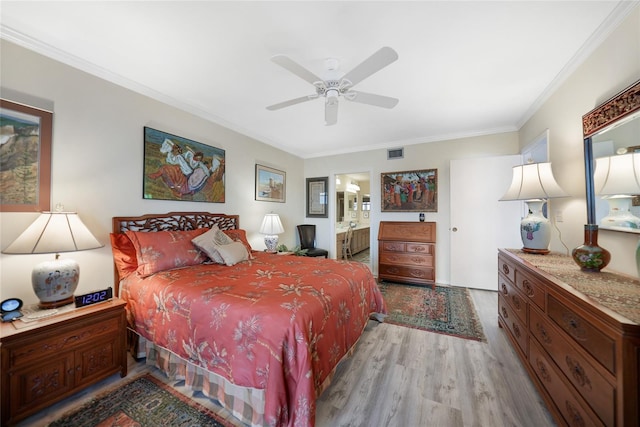 bedroom featuring light wood-type flooring, ensuite bath, ceiling fan, and crown molding