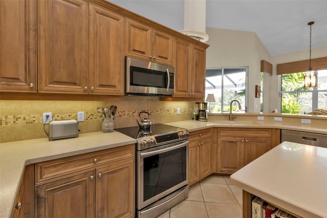 kitchen featuring appliances with stainless steel finishes, hanging light fixtures, tasteful backsplash, light tile patterned floors, and sink