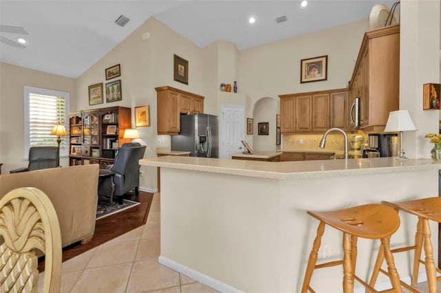 kitchen with light tile patterned floors, sink, kitchen peninsula, appliances with stainless steel finishes, and a kitchen bar