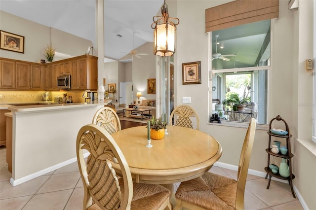 tiled dining area featuring ceiling fan, sink, and vaulted ceiling