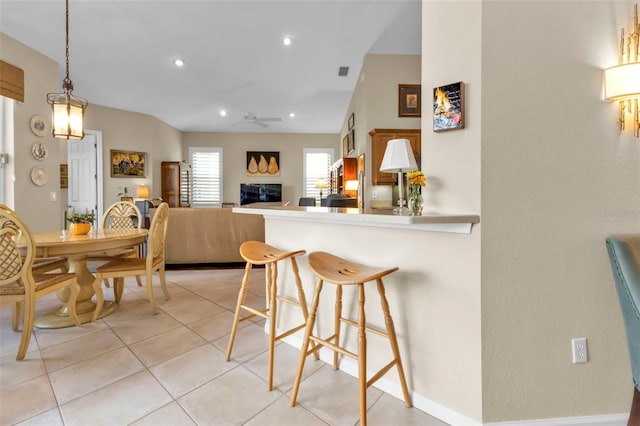 kitchen featuring a breakfast bar, kitchen peninsula, hanging light fixtures, light tile patterned floors, and ceiling fan