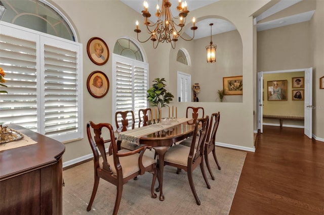 dining room with an inviting chandelier, a towering ceiling, and hardwood / wood-style floors