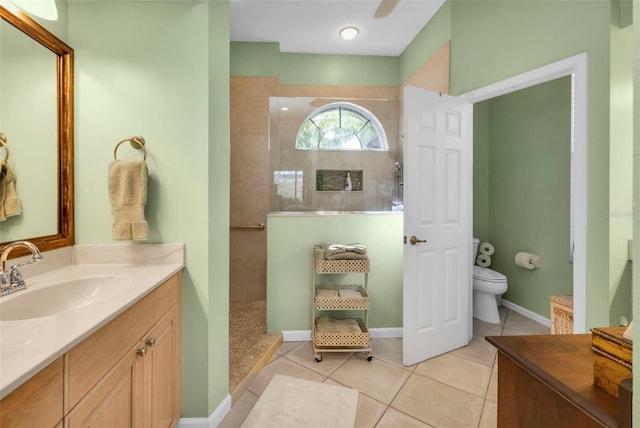 bathroom featuring tile patterned flooring, tiled shower, vanity, and toilet