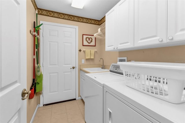 laundry room featuring light tile patterned floors, cabinets, sink, and washing machine and dryer