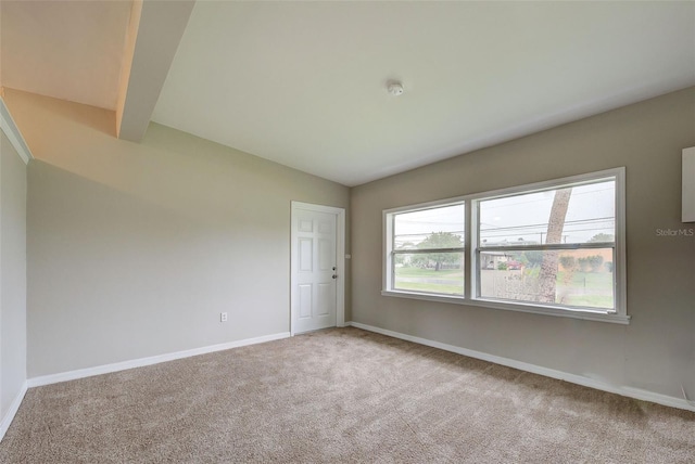 carpeted empty room featuring vaulted ceiling with beams