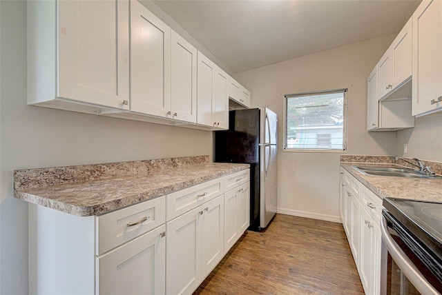 kitchen featuring wood-type flooring, white cabinets, stainless steel appliances, and sink