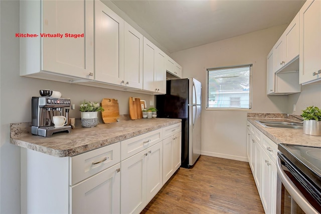 kitchen with white cabinets, light hardwood / wood-style floors, appliances with stainless steel finishes, and sink