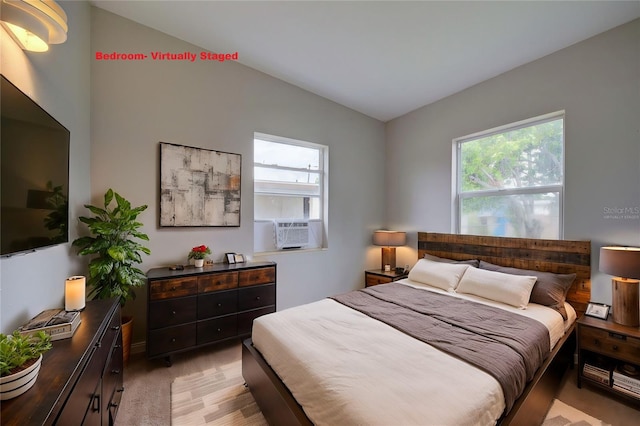 bedroom featuring multiple windows, cooling unit, lofted ceiling, and light hardwood / wood-style floors