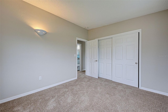 unfurnished bedroom featuring light carpet and a closet