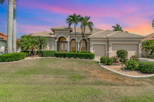 mediterranean / spanish-style home featuring a lawn and a garage