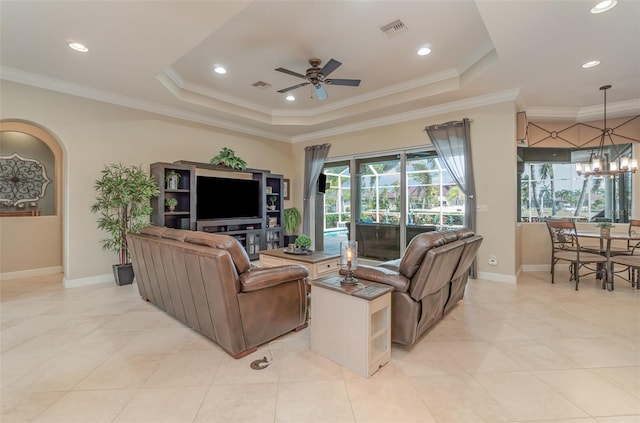 tiled living room with ornamental molding, a tray ceiling, and ceiling fan with notable chandelier