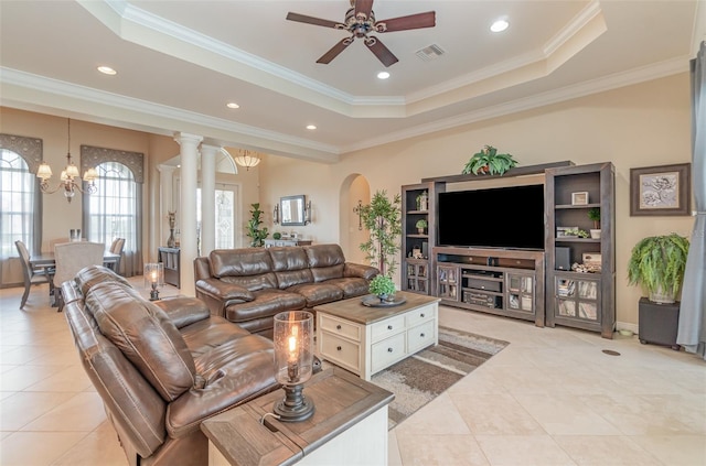 tiled living room with ornate columns, crown molding, a tray ceiling, and ceiling fan with notable chandelier