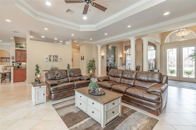 tiled living room featuring french doors, a raised ceiling, decorative columns, ceiling fan, and crown molding