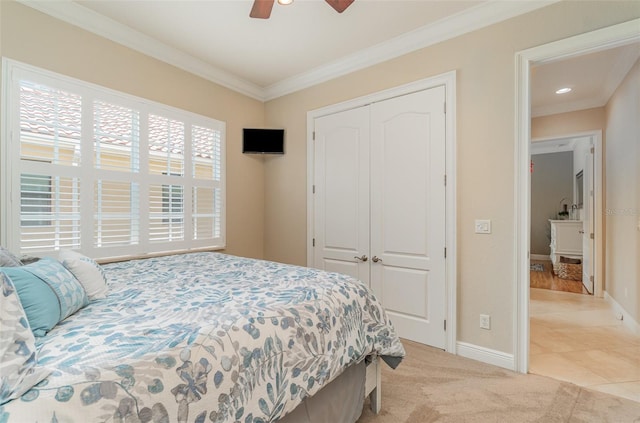 carpeted bedroom with a closet, ornamental molding, and ceiling fan