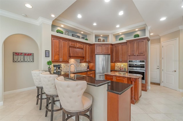 kitchen with appliances with stainless steel finishes, a kitchen bar, a center island, kitchen peninsula, and custom exhaust hood