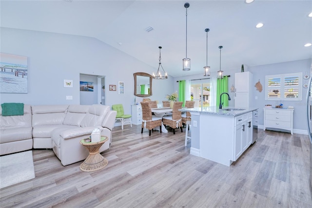 kitchen featuring sink, white cabinetry, light hardwood / wood-style flooring, decorative light fixtures, and light stone countertops