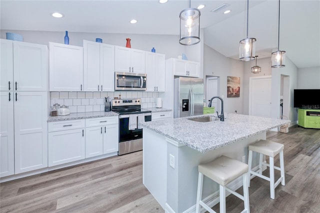 kitchen featuring stainless steel appliances, white cabinets, hanging light fixtures, and sink