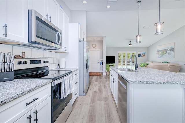 kitchen with hanging light fixtures, sink, a center island with sink, white cabinetry, and appliances with stainless steel finishes