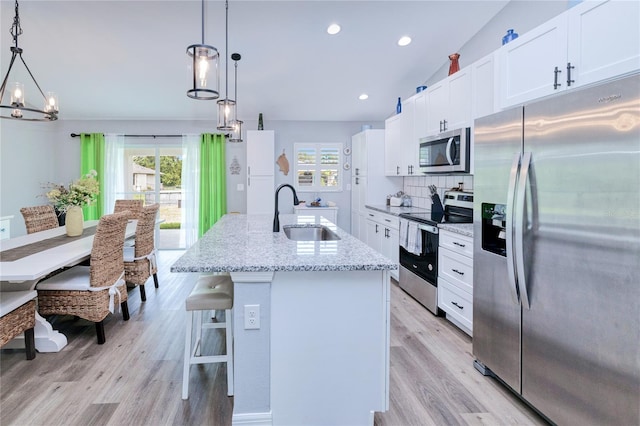 kitchen featuring an island with sink, stainless steel appliances, white cabinets, and sink