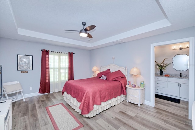 bedroom featuring light hardwood / wood-style floors, a tray ceiling, and ceiling fan