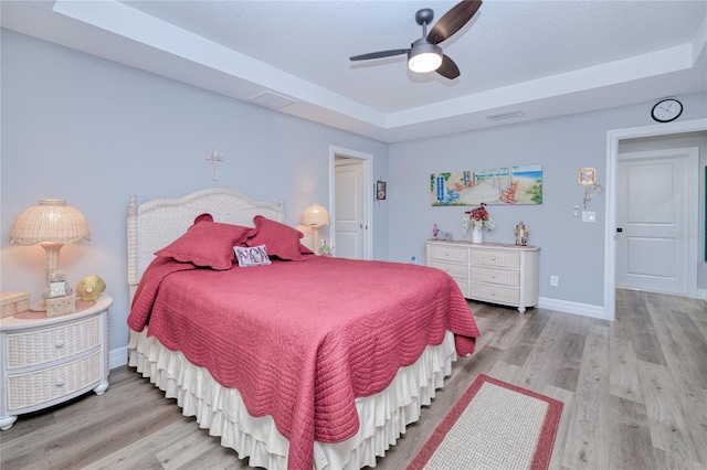 bedroom featuring wood-type flooring, a tray ceiling, and ceiling fan