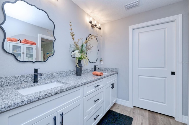 bathroom featuring wood-type flooring, vanity, and a textured ceiling