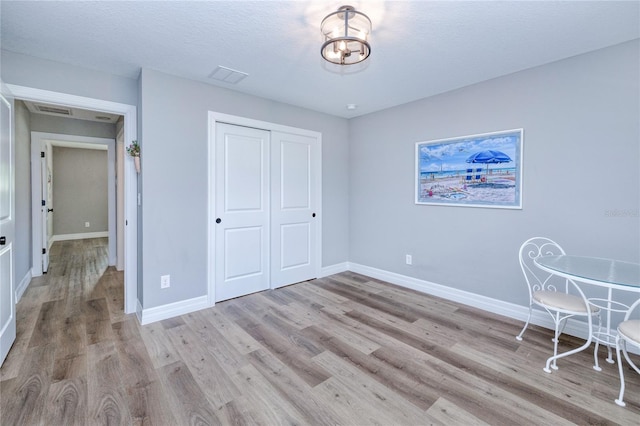 unfurnished bedroom featuring a textured ceiling, a closet, and light hardwood / wood-style floors